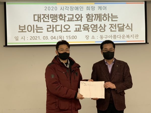 세 주체(대전대,대전맹학교, 작은극장 다함)를 대신해 작은극장 다함 김영태 대표(왼)가 동구 아름다운복지관 최재천 관장(오)에게 교육자료를 전달하고 있다.