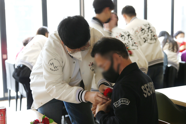 어버이날을 맞아 총학생회 임원이 보안노동자에게 카네이션을 달아드리고 있다.