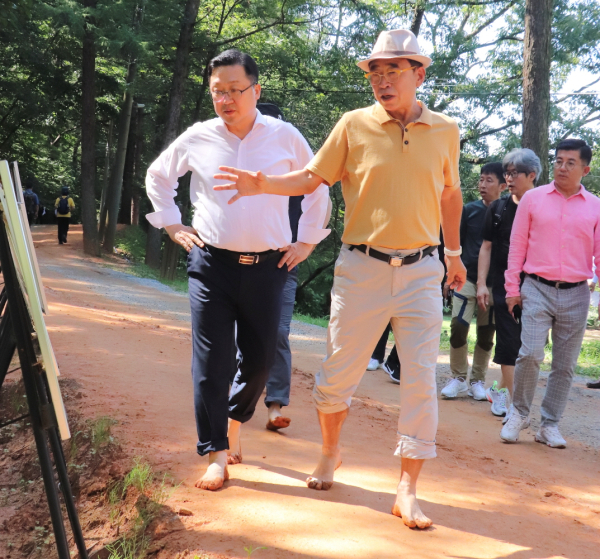 계족산황톳길을 맨발로 걷고있는 이장우 대전시장(좌)과 조웅래 맥키스컴퍼니 회장(우)