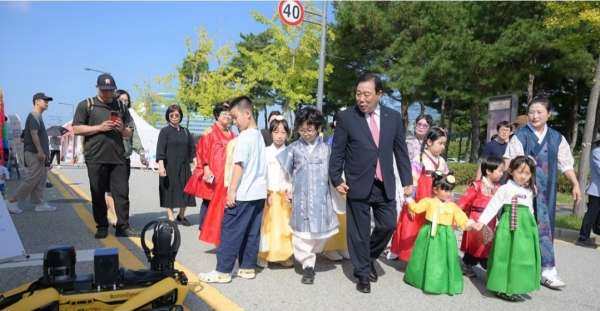 한글 문양이 새겨진 한복을 입은 어린들과 함께 축제 거리를 걷는 최민호 시장